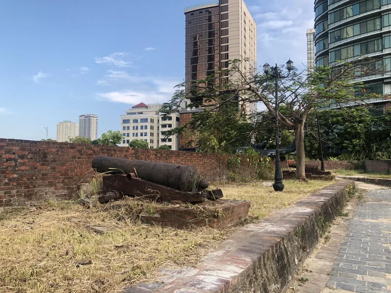 An old cannon rests on brick ruins at Dien Hai Citadel in Da Nang, with modern towers behind. An old cannon rests on brick ruins at Dien Hai Citadel in Da Nang, with modern towers behind.
