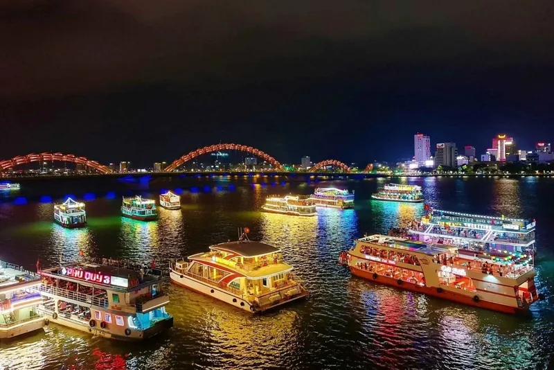 Illuminated cruise boats float on the Han River at night with Dragon Bridge lit up in Da Nang. Illuminated cruise boats float on the Han River at night with Dragon Bridge lit up in Da Nang.