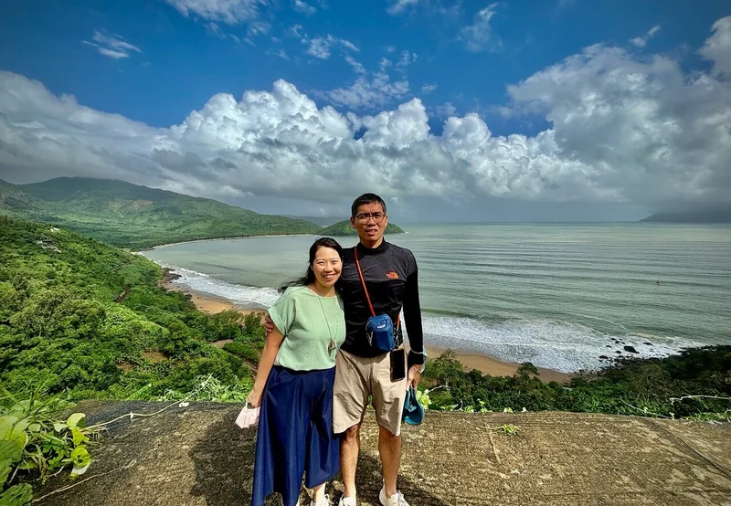 A couple poses on a coastal viewpoint overlooking a curved bay along the Hai Van Pass between Hue and Hoi An. A couple poses on a coastal viewpoint overlooking a curved bay along the Hai Van Pass between Hue and Hoi An.